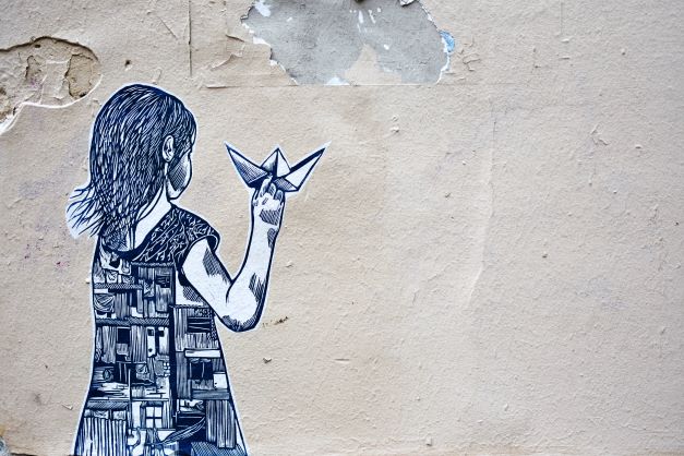 Graffiti of back of a girl with a paper plane