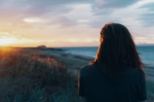 woman looking at ocean over sunset