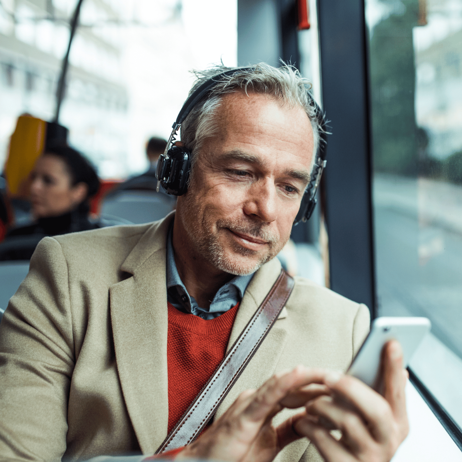 Picture of a man on public transport looking at his phone.