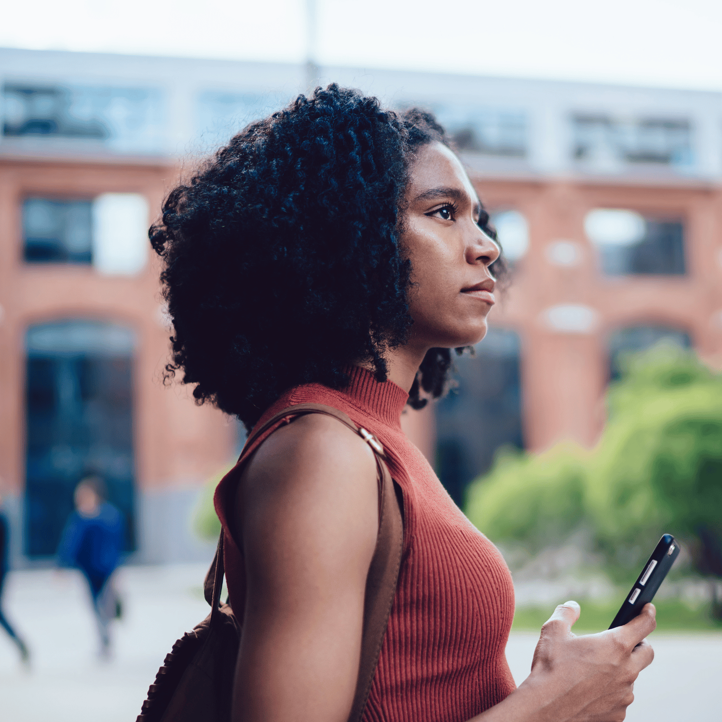 Picture of a woman looking into the distance with a phone in her hand.